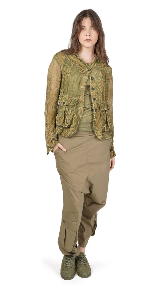 Person trägt olivgrüne, abgewetzte Jacke mit weitem Schnitt und passende Cargo-Pantalons, schlichtes Oberteil.