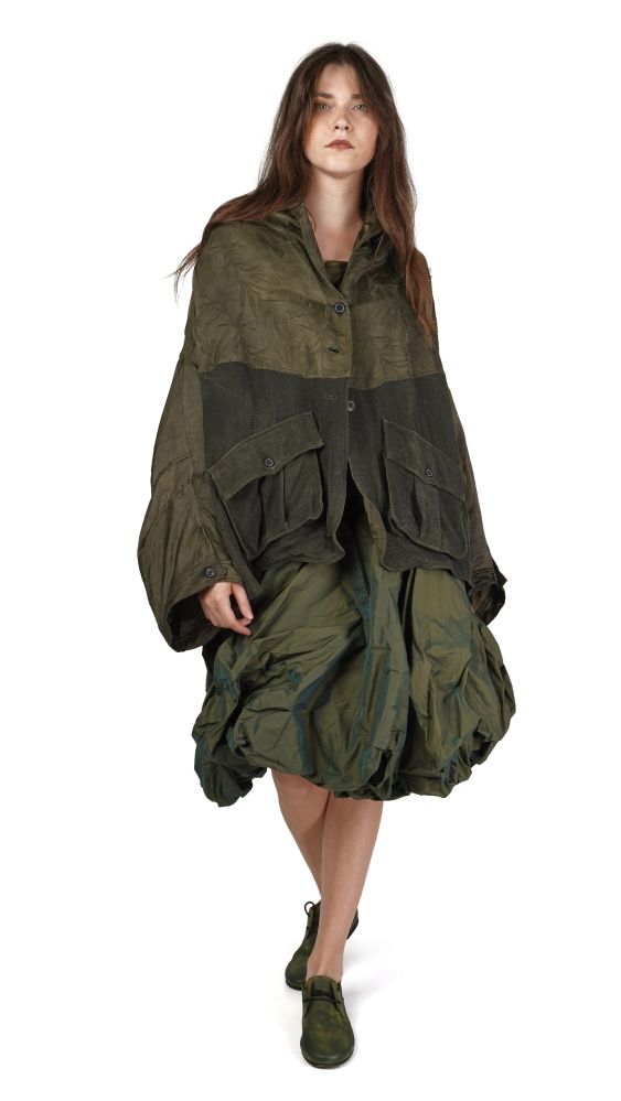 Frau trägt oversized olivgrünes Jacken-Kleid mit weiten Ärmeln und Puffröcken, kombiniert mit grünen Pumps.