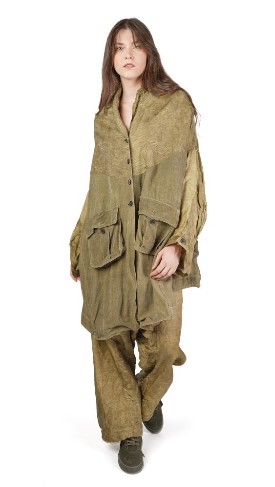 Person trägt oversized khakifarbenes, zerrissenes Overall-Kleid mit Kapuze und schwarzen Stiefeln.