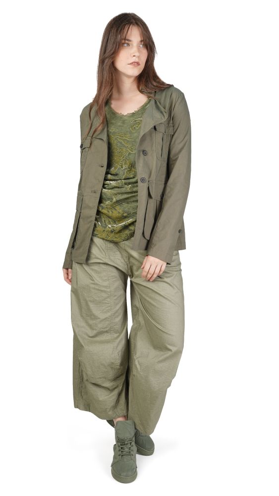 Frau trägt olivgrüne Jacke, weite Hose und gemustertes Top mit robusten Stiefeln.