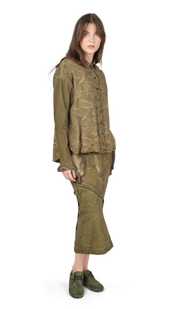 Frau trägt olivgrünes, oversized Anzug-Set mit abgewetzten Details und grünen Schuhen.