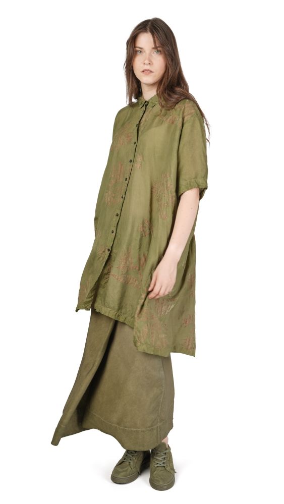Frau trägt oversized olivgrünes Kleid mit weitem Schnitt und grünen Stiefeln.