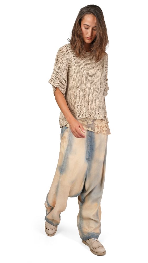 Person trägt oversized beige Strickshirt, ausgebleichte Hosen und bequeme Schuhe.