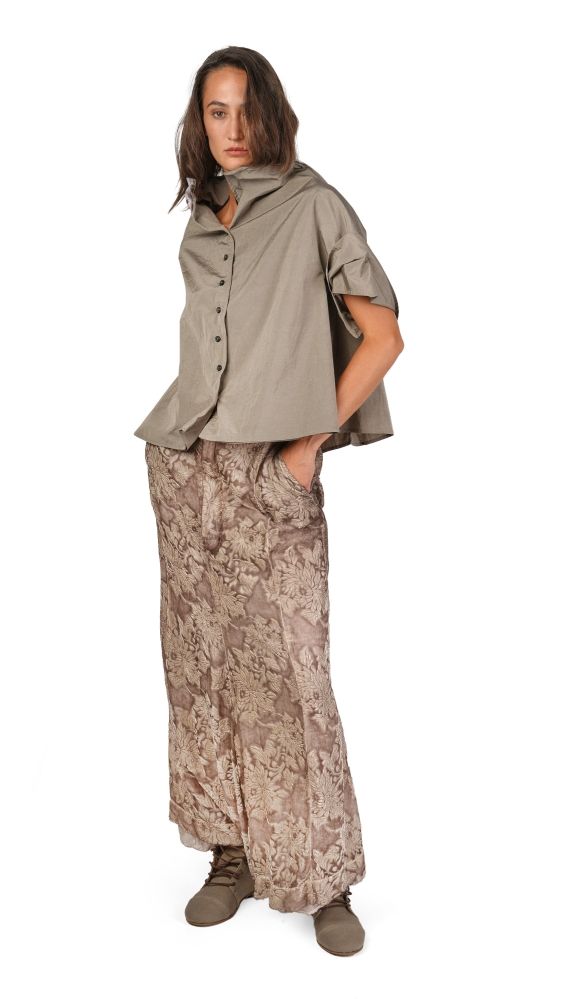 Person trägt oversized beige Hemd mit weitem Rock und robusten Stiefeln, lässiger Stil.
