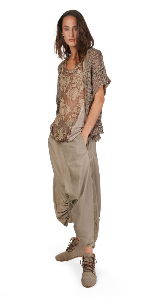 Frau trägt bohemisches Top mit Muster, oversized Bluse und weite beige Hosen mit Sneakern.