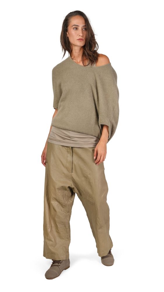 Frau trägt bequeme, oversized beige Bluse mit hochtailligen, weiten Hosen und flachen Schuhen.