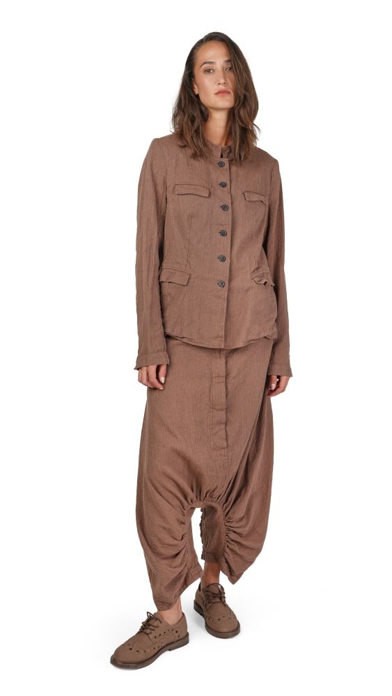 Frau trägt beiges oversized Jumpsuit mit weiten Hosenbeinen und flache Schuhe.