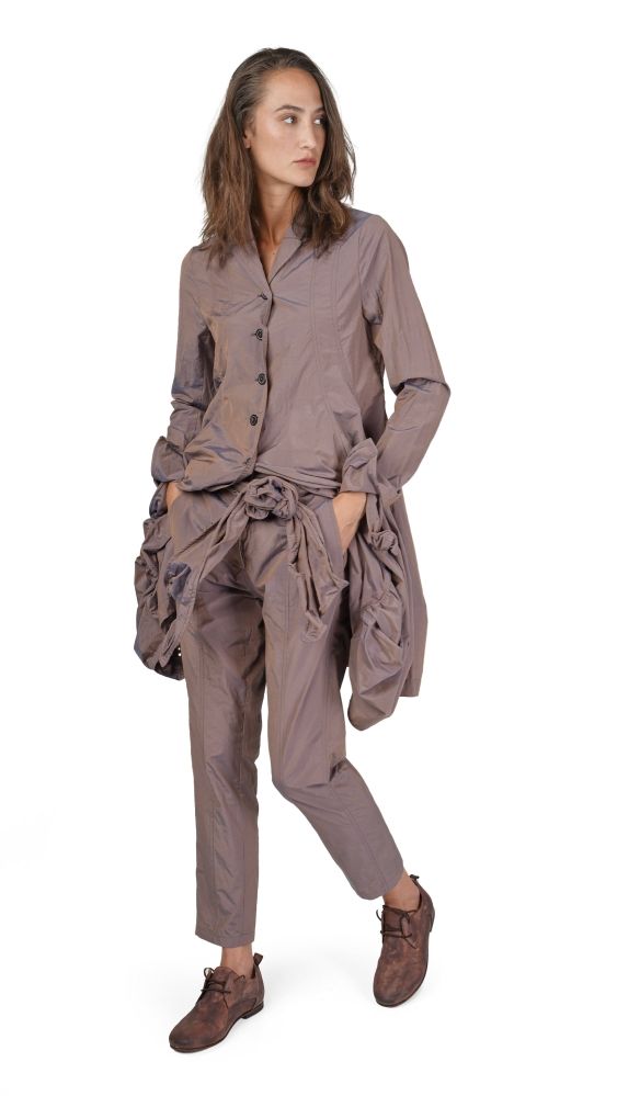 Frau trägt oversized beige Bluse mit weiten, zerknitterten Hosen und braunen Stiefeln.