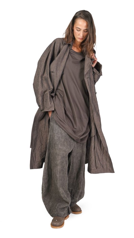 Person trägt lässigen, oversized dunklen Mantel mit weitem Schnitt und bequemen Hosen.