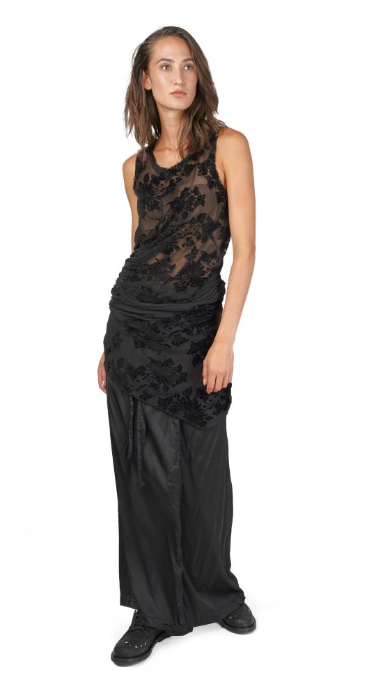 Schlanke Person in schwarzem, langem Kleid mit floraler Spitzenapplikation und Anklang an Boho-Stil.