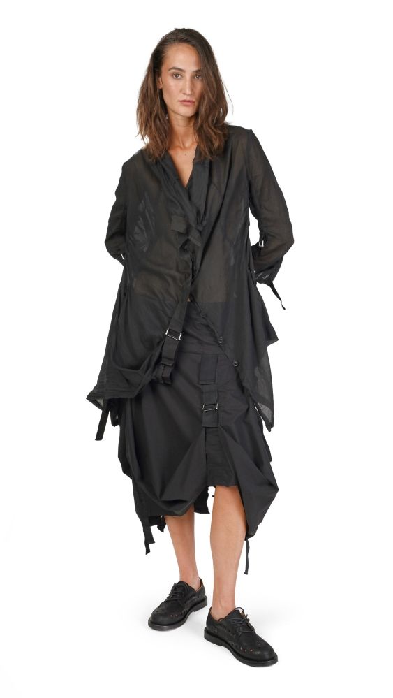 Frau trägt oversized schwarzen Cape-Bademantel mit Gürtel und Sneakers.