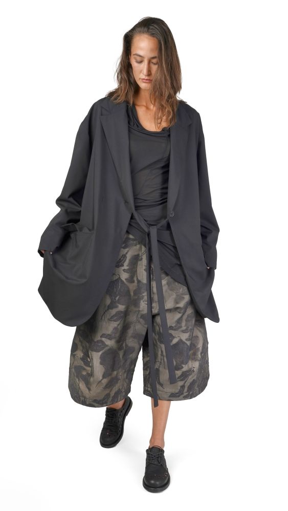 Frau trägt oversized Blazer, camouflage Pantalons und schwarze Schuhe, lässiger Stil.