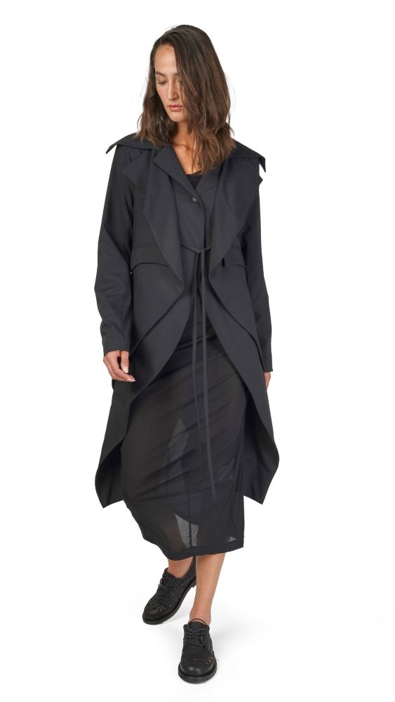 Langer schwarzer oversized Mantel mit asymmetrischen Ärmeln und Gürtel, getragen mit schwarzen Stiefeln.