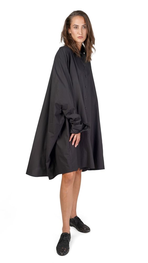 Frau trägt eleganten schwarzen Cape-Rock mit kurzem Kleid und schwarzen Schuhen.