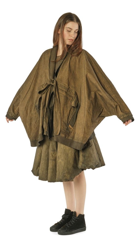 Frau trägt oversized olivgrünes Cape-Kleid mit Gürtel und schwarzen Stiefeln.