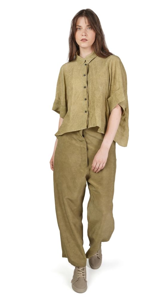 Frau trägt olivfarbenes oversized Hemd und weite Hosen, lässiger Look.