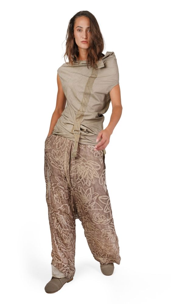 Person trägt beige, gemusterte Hosenanzug-Kombi mit weitem Oberteil und Gürtel, steht lässig.