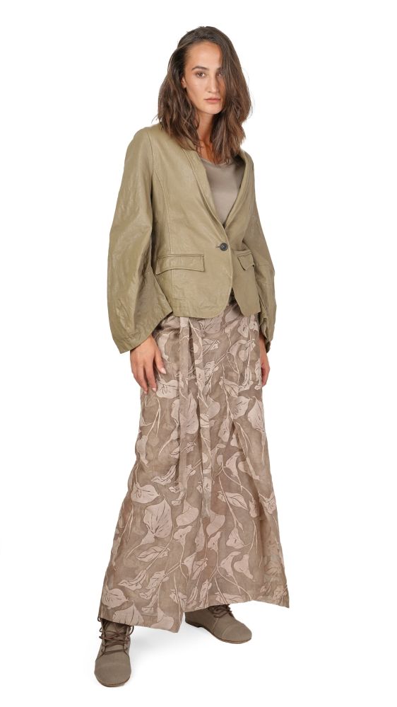 Frau trägt olivfarbene Jacke mit Blumenkleid und braunen Stiefeln, lässiger Stil.