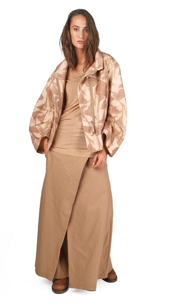 Frau trägt beige Musterjacke, langes Wickelkleid und flache Schuhe.
