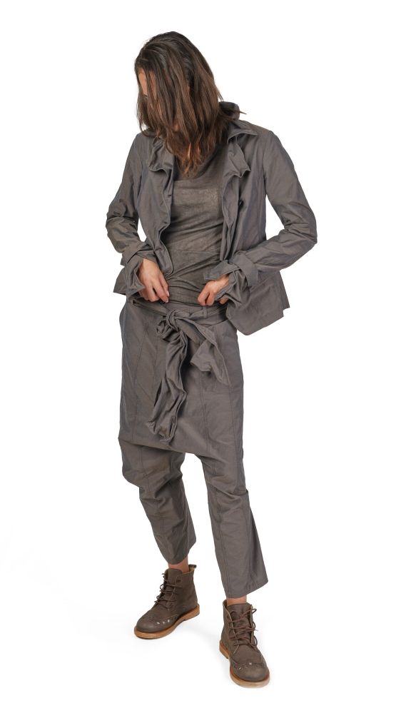 Person trägt graue oversized Jacke, weiten Jumper und harlekinartige Hosen mit Stiefeln.