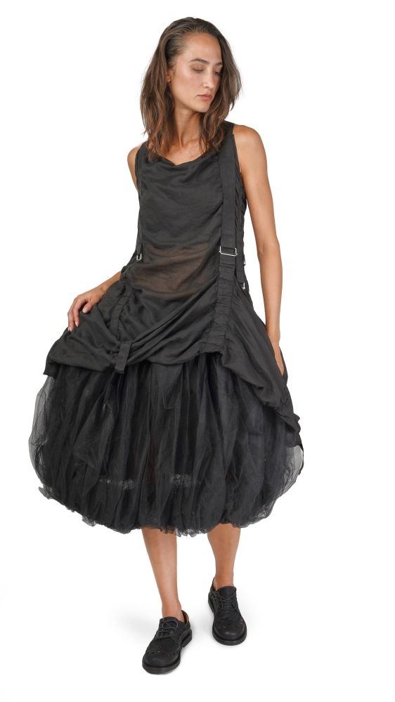 Schwarzes, elegantes Kleid mit Pailletten-Rock und durchsichtigen Elementen, kombiniert mit schwarzen Stiefeln.